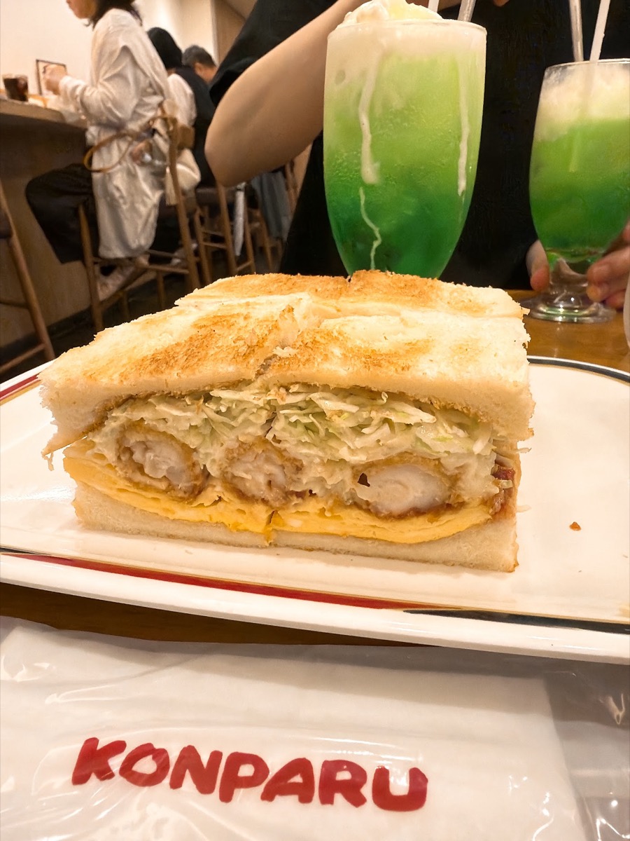 コンパル サンロード店の名物エビフライサンド 断面にエビフライとキャベツとタルタルソース KONPARUの赤いロゴ入りトレー